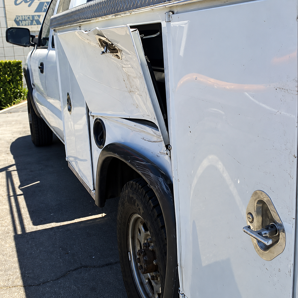 White work truck with a crushed utility compartment door and bent metal panel above its rear wheel.