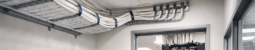 Server room viewed through a doorway, showing overhead cable pathways leading into a fully organized network rack.