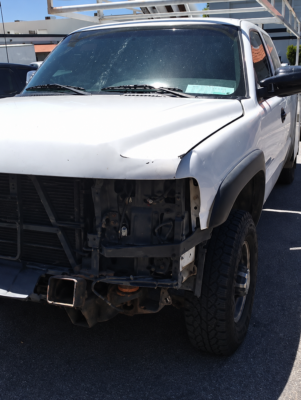 White utility pickup with front bumper, grille, and one headlight removed, exposing internal front-end components.
