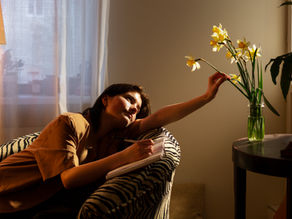 A person journaling and engaging in self-reflection while sitting in a sunlit room.