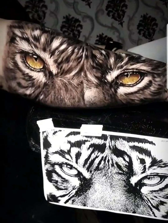 tatuagem realista com olhos de tigre no antebraço