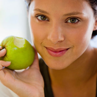 woman smiling with a bitten green apple