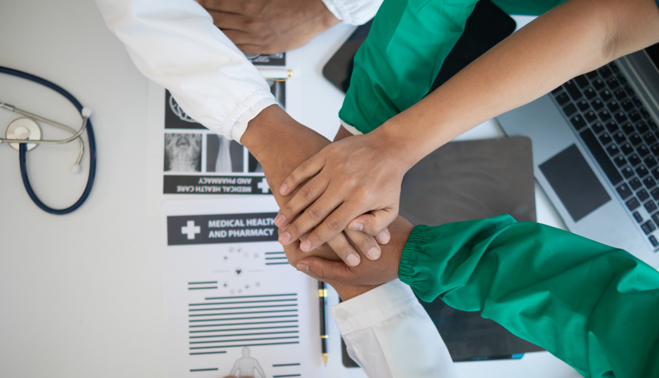 Health care professionals showing unity with hands together, symbolising collaborative strength and support