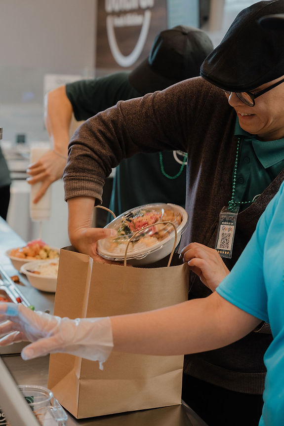 Boltiful staff packing a fresh healthy bowl into a paper takeout bag at the counter