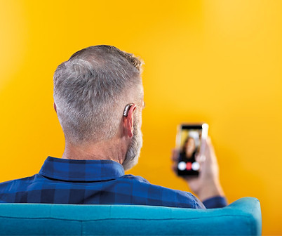 pessoa buscando informações no smartphone com conectividade bluetooth no aparelho auditivo Philips e