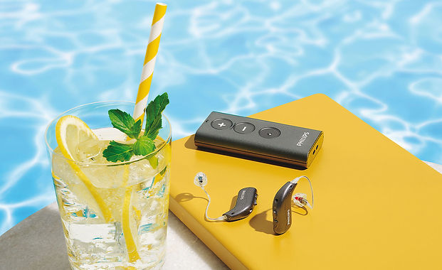 aparelho auditivo Philips Hearlink em uso em ambiente externo ao ar livre mostrando a sua beleza discreto pequeno muito tecnológico e com muitas possibilidades de conexão conectividade bluetooth com outros aparelhos smartphones e celulares resistente contra humidade e água IP67 IP68