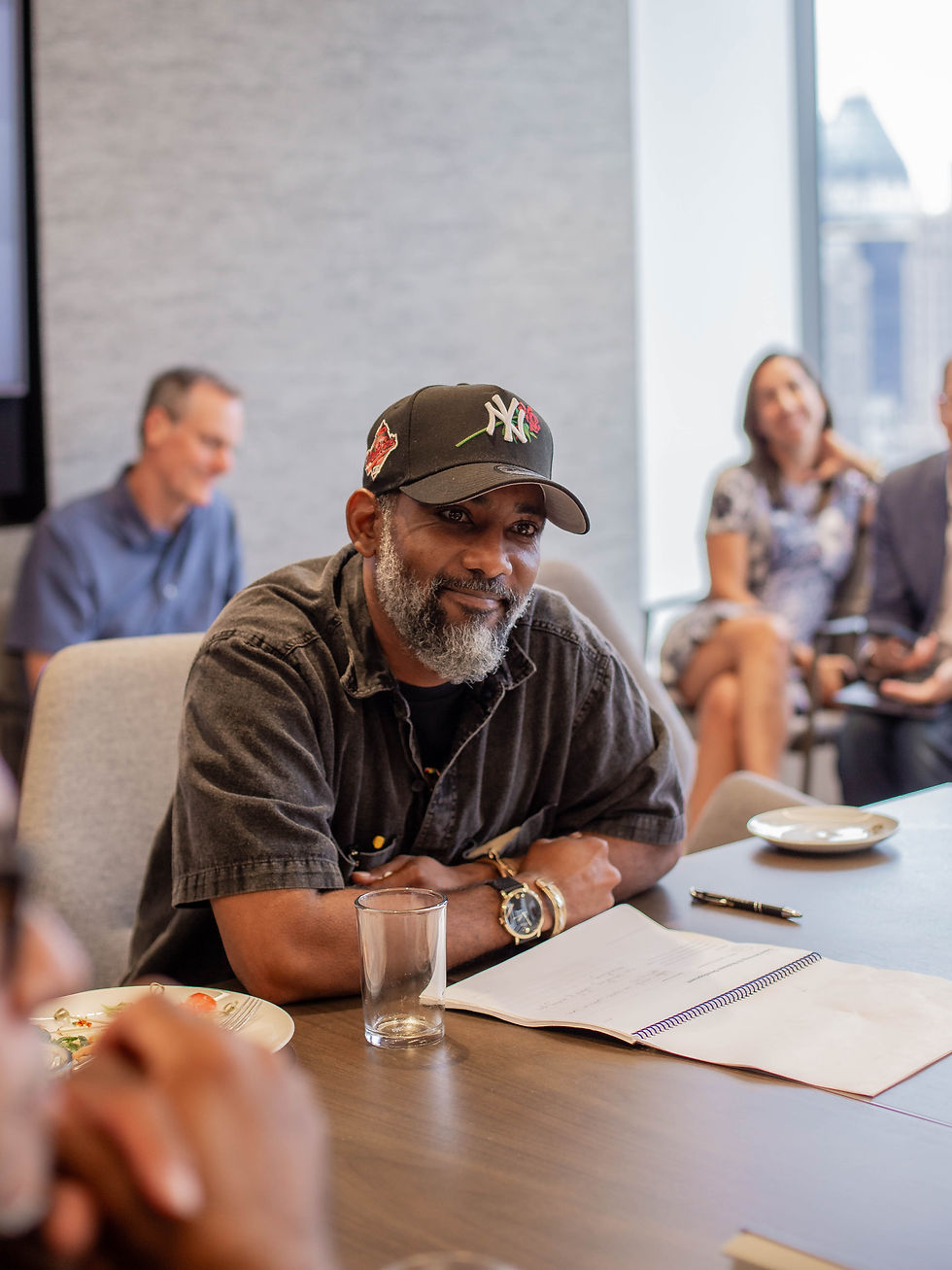 Island Pops small business owner Khalid seated at a conference table listening attentively at the TAP and Apollo Opportunity Foundation Summer Small Business Summit