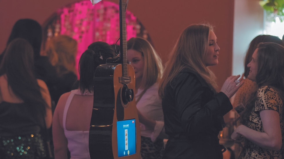 A Guitar Shaped Photo Booth is shown surrounded by a group of people attending a corporate/social/wedding party/event in Denver, Colorado
