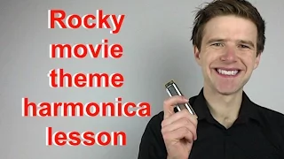 Image on man smiling and holding harmonica in front of grey backbground. Text: "Rocky movie theme harmonica lesson"