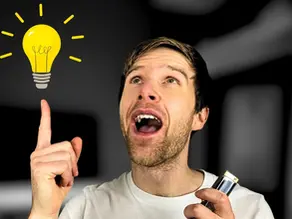 Man laughing with joy, holding harmonica and pointing upwards with his free hand at a cartoon shining yellow lightbulb.