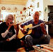 A man playing the guitar, and a woman playing the harmonica, in a living room scene