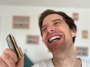 Man holding harmonica and laughing joyously
