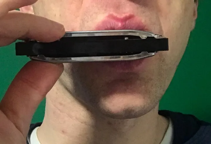 Man playing harmonica with U-block mouthshape.