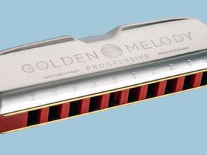 Silver harmonica with red accents on blue background, featuring "Golden Melody" and numbered holes 1-10 with text "Made in Germany."