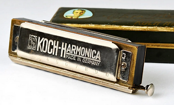 Hohner Koch harmonica and case on white background.