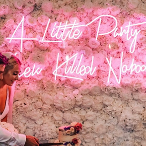 bride and groom cutting cake in front of Pink a little party never hurt nobody neon sign