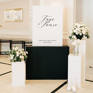 monochrome wedding welcome sign. white plinths with ivory florals