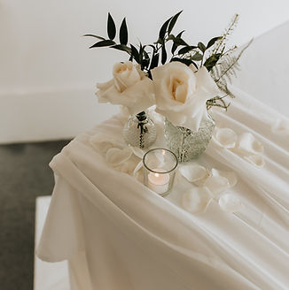 ivory roses in budvases with tealights and petals