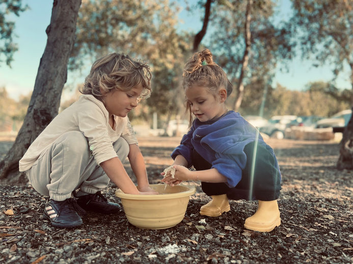 שני ילדים מכינים בצק לפיתות בטאבון
 ילדי החורש מונטסורי יער