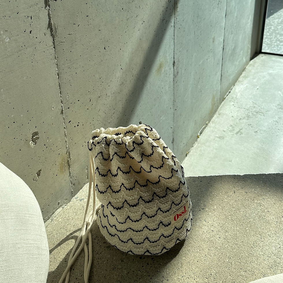 Thumbnail: Close-up of crochet drawstring pouch with black wave stitch and red Ossl logo.