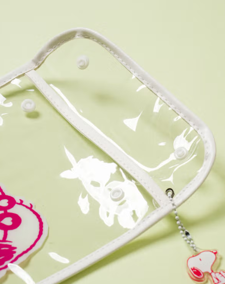 Thumbnail: Snoopy clear PVC pouch filled with cosmetics and sunglasses on pastel background.