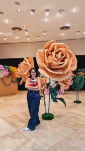 Artista Jacqueline Benevides ao lado de uma das suas obras