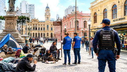 População em situação de rua ocupando área do Centro Histórico de Curitiba, próximo à Praça Tiradentes, com comércio e pedestres ao redor.