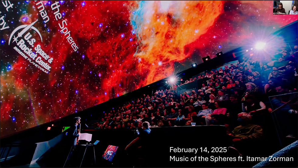 Violinist performing alone on stage beneath a full dome of red and orange nebula imagery, to a packed house