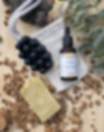 Savon de massage noir, savon couleur sable, huile bio et un pochon en rami et le tout a base d'argan poser sur une planche