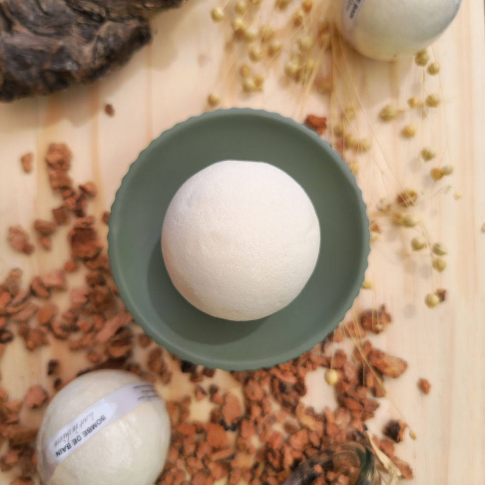 Bombe de bain Lait de chèvre posée sur socle vert d'eau sur une planche en bois et des copeaux, entourée de boules blanches