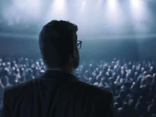 Man on stage speaking to audience.