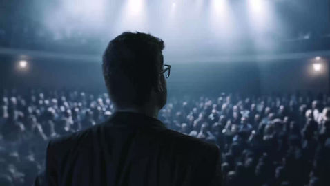 Man on stage speaking to audience.