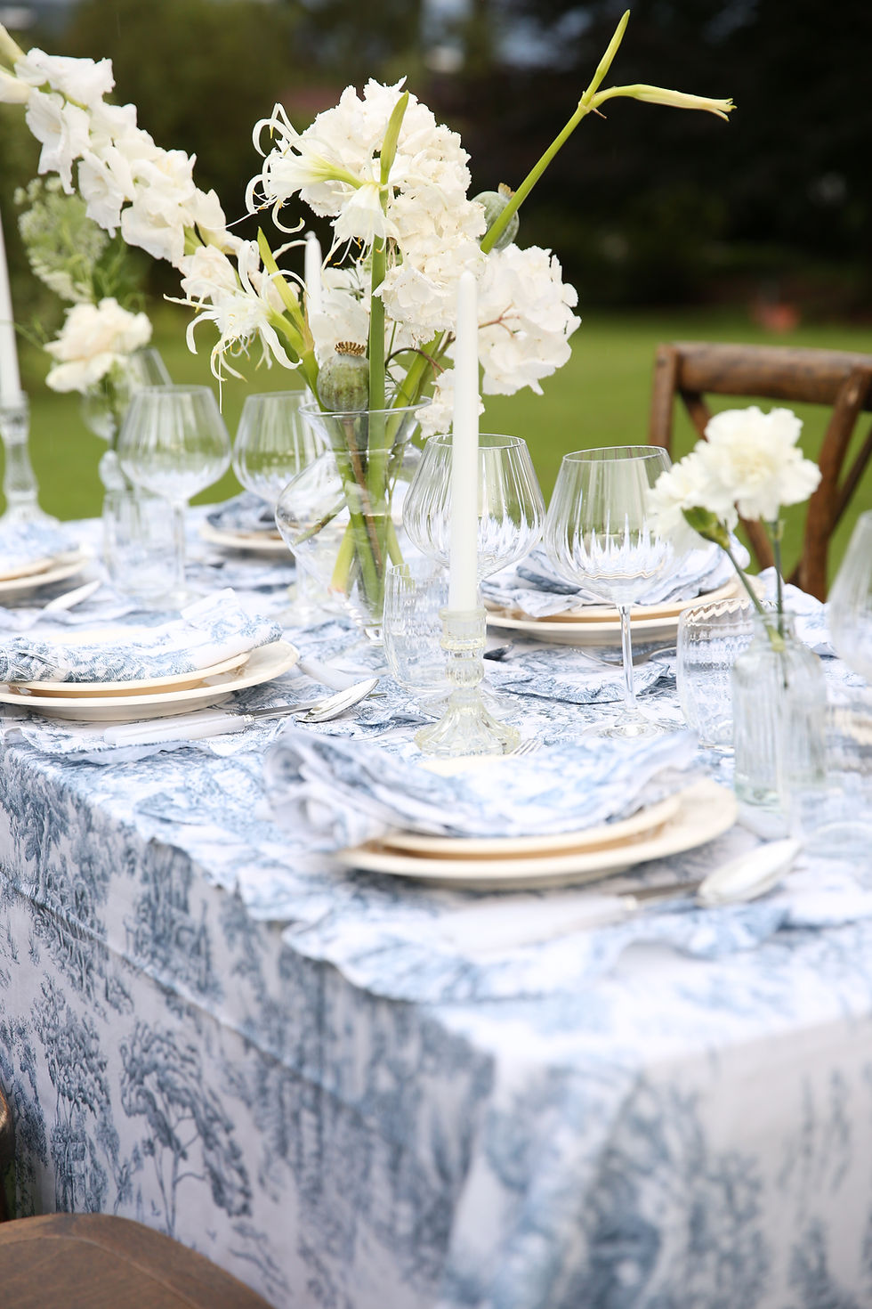 Miniaturbild: Nahaufnahme eines gedeckten Tisches mit blauer Toile-de-Jouy-Tischdecke, elegant und zeitlos.