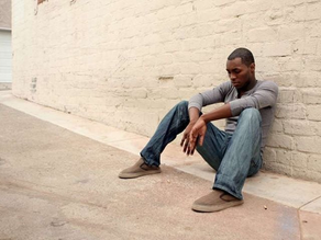 Man sitting alone against  a wall