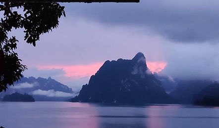Sunset and mist over the limestone cliffs of Cheow Lan Lake during an evening wilderness expedition.