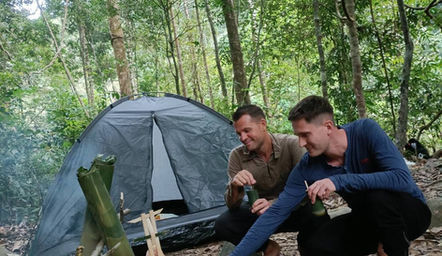 Travelers setting up a jungle campsite beside a stream in Khao Sok National Park.