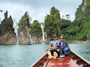 Longtail boat passing limestone cliffs on Cheow Lan Lake