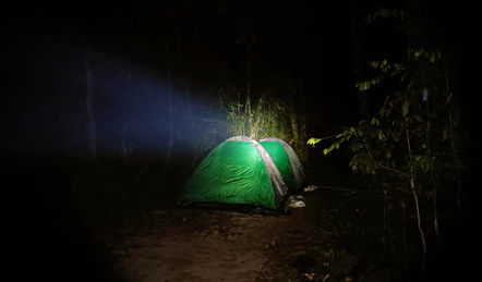 Night camping atmosphere in Khao Sok with illuminated tent deep in the rainforest.