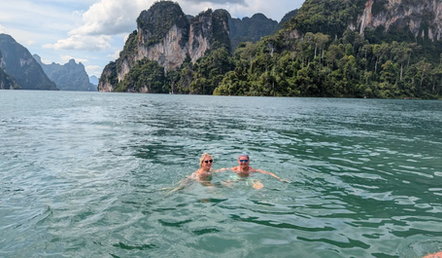 Travelers swimming in the emerald waters of Cheow Lan Lake surrounded by limestone mountains.