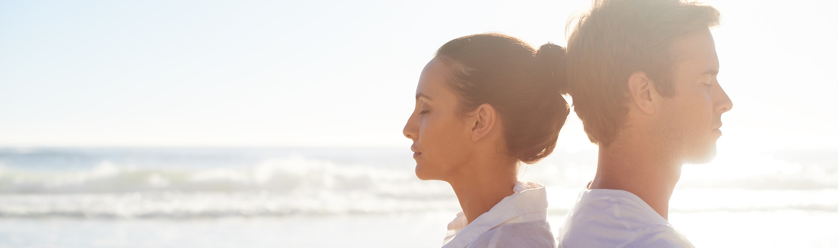 Pareja meditando en la playa