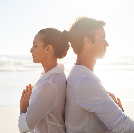 Paare, die auf dem Strand meditieren