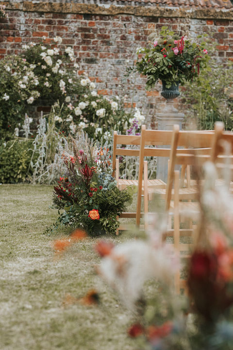Outdoor garden wedding ceremony flowers of rustic meadow arrangements and large flower urn at Midelney Manor Langport Somerset.