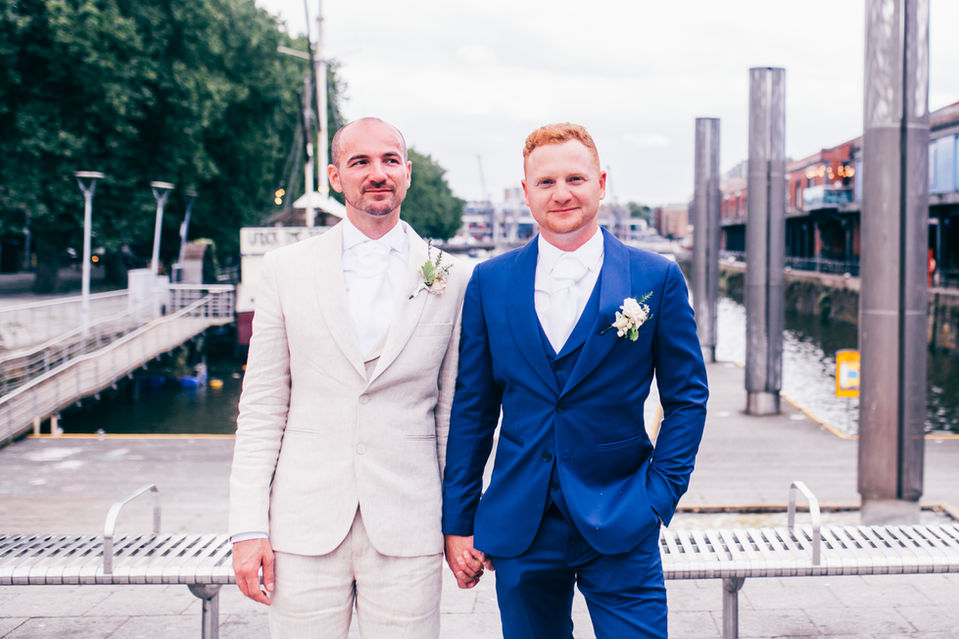 Both Grooms wearing wedding buttonholes after LGBTQ wedding ceremony at Bristol Registry Office enroute to wedding reception at Goldney Hall Clifton in Bristol.