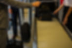 Passengers placing luggage on a conveyor belt for X-ray screening at an airport security checkpoint, emphasizing safe and secure travel procedures.