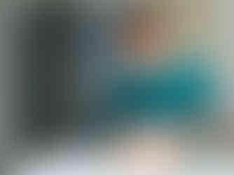 Close-up of a black and white cat on an operating table with surgical tools and a green drape during surgery.