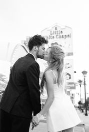 bride and groom wearing formal attire embrace each other outside of the little white wedding chapel in las vegas