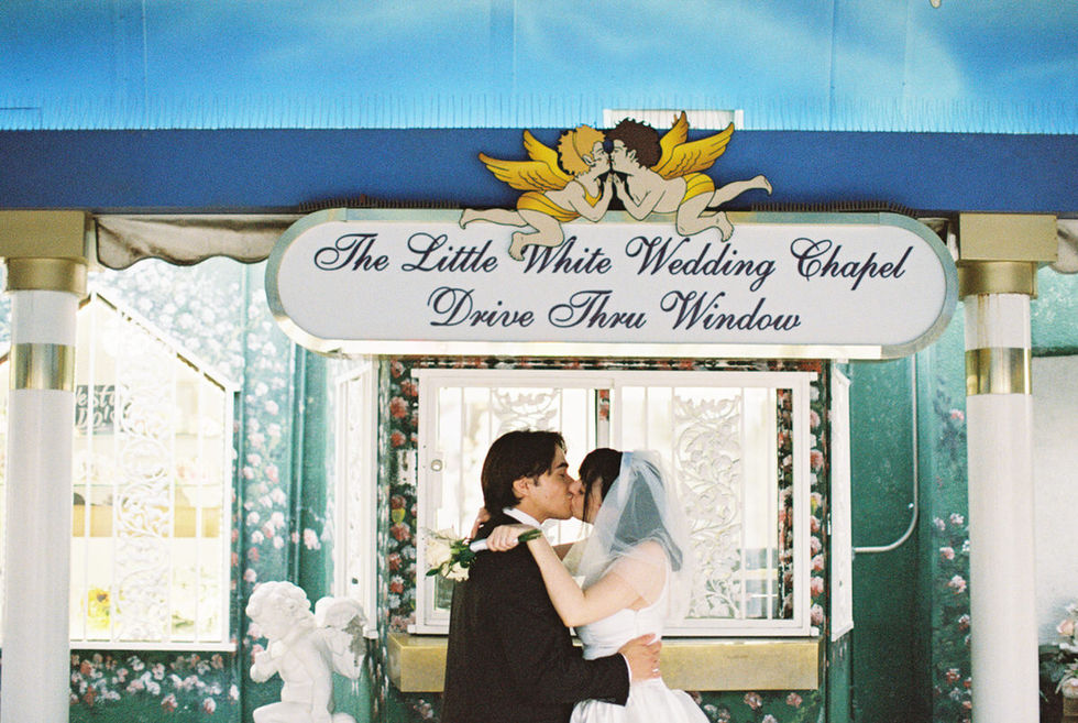 bride and groom wearing wedding attire hold hands in the tunnel of love at the little white wedding chapel with cupid mural overhead