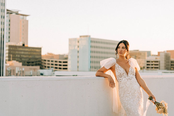 Bride and groom pose for pictures in downtown las vegas at golden hour with the strip in the background. captured by las vegas wedding photographer brazen honey films. Groom wears stylish stottish kilt. Bride wears custom made with love bridal gown.