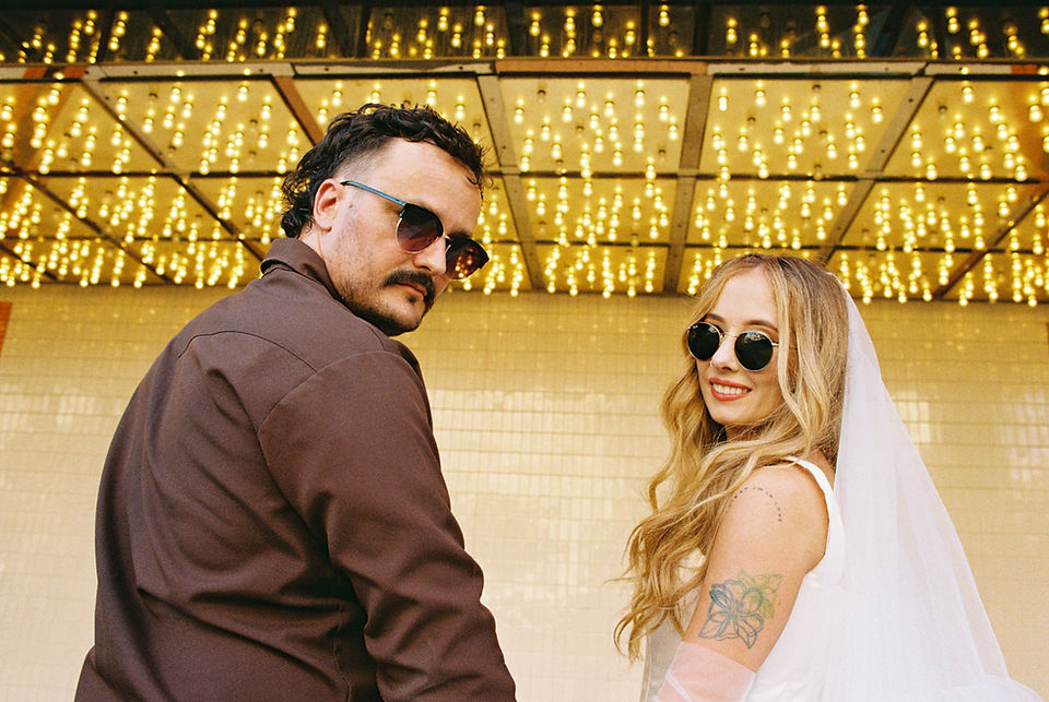 35mm film photo by las vegas elopement photographer brazen honey films. couple takes pictures in downtown las vegas with neon lights and vintage vibes.