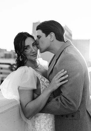 Bride and groom pose for pictures in downtown las vegas at golden hour with the strip in the background. captured by las vegas wedding photographer brazen honey films. Groom wears stylish stottish kilt. Bride wears custom made with love bridal gown.
